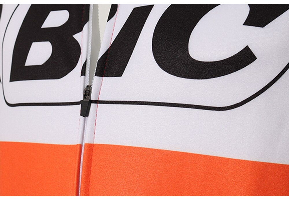 Close-up of a BIC Orange Long Sleeve Retro Cycling Jersey, featuring bold black BIC lettering on a white background with an orange band below. A visible vertical zipper runs through the center.