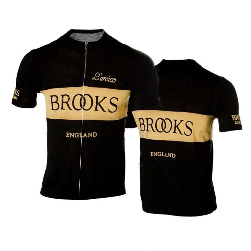 Two Brooks England Retro Cycling Jerseys in black feature beige stripes and the text Leroica, Brooks England, and ENGLAND on the front. The back displays BROOKS, mirroring the sleeve branding; ideal for those after a performance jersey with vintage flair.
