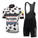 The Reynolds Aluminio Retro Cycling Jersey Set celebrates the 1989 Vuelta a España with a white short-sleeve jersey adorned with black polka dots, multicolored stripes, and Reynolds Aluminio text, paired with sleek black bib shorts featuring the same iconic branding.