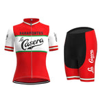 The Womens La Casera-Bahamontes Retro Cycling Jersey Set features a red and white short-sleeve jersey with a front zipper, green accents, and bold branding. The mostly black shorts have striking red sides.