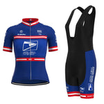 The Womens US Postal Service Jersey Set features a blue and black short-sleeve jersey with red and white stripes, logos, and a front zipper, paired with black breathable shorts with blue panels. Both pieces display the USPS emblem prominently.