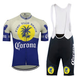 Check out the Corona Beer Retro Cycling Jersey Set, complete with a full-length zipper and gel seat pad. The short-sleeve jersey and bib shorts display a vibrant yellow circle, blue palm trees, and Find Your Beach text on a mainly blue and white background.