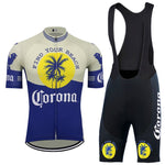 Introducing the Corona Beer Retro Cycling Jersey Set: a blue and yellow tropical design with palm tree motifs and Find Your Beach text. It includes a short-sleeve jersey with a full-length zipper and black bib shorts, both featuring comfortable gel seat pads.