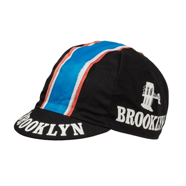 A black retro cycling cap with a blue, white, and red stripe. The classic design features BROOKLYN in white letters on the side and brim, echoing Brooklyn Chewing Gums iconic style. Product: Brooklyn Retro Cycling Caps.