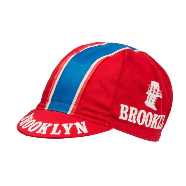Red retro cycling cap featuring classic Brooklyn text and bridge motif, echoing Brooklyn Chewing Gum charm with blue and white center stripes for a timeless feel. Product Name: Brooklyn Retro Cycling Caps.