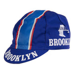 The Brooklyn Retro Cycling Caps showcase red, white, and blue stripes with BROOKLYN printed on the brim and side, complemented by a bridge graphic that captures the classic style of Brooklyn Chewing Gum.