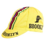 The Brooklyn Retro Cycling Cap features a classic design with BROOKLYN in black on the brim and side, multicolored stripes (red, blue, green) from top to back, and a small factory graphic. Ideal for vintage style enthusiasts.