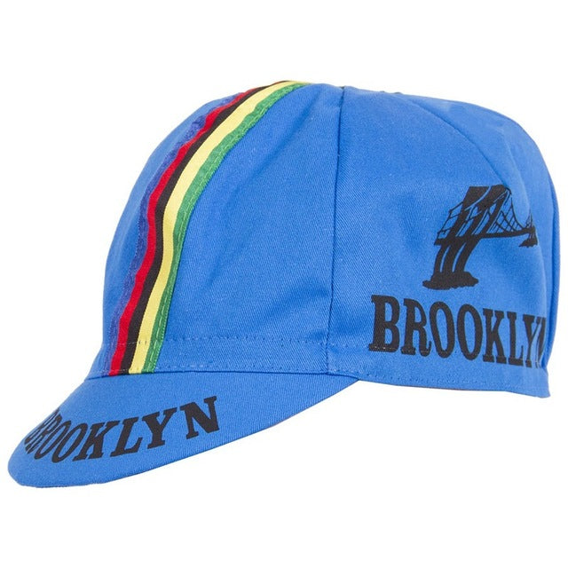 The Brooklyn Retro Cycling Cap features Brooklyn in black with a bridge graphic. Inspired by Brooklyn Chewing Gum, it has green, yellow, and red stripes across the top for a timeless charm.