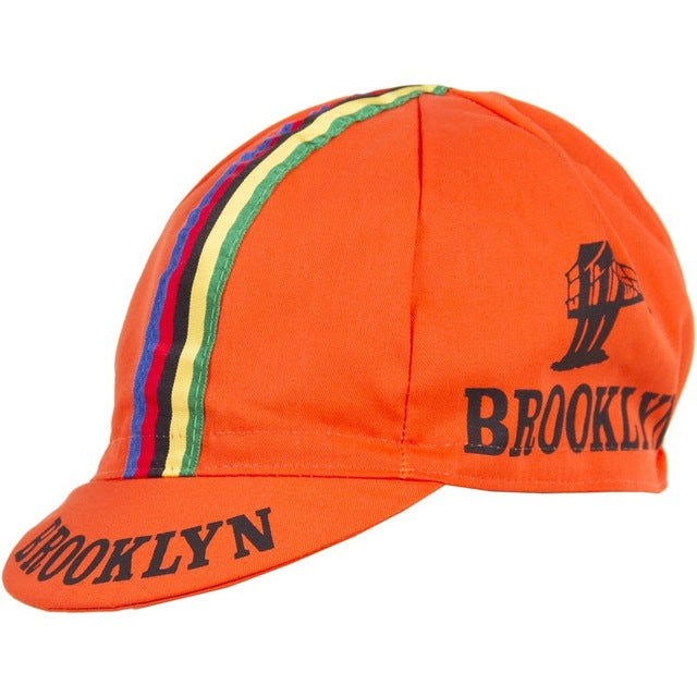 The Brooklyn Retro Cycling Cap in orange features a short brim, vibrant blue, green, yellow, and red stripes, with Brooklyn and a bridge logo in black, capturing the nostalgic charm of Brooklyn Chewing Gum.