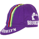 The Brooklyn Retro Cycling Cap boasts a classic purple design with a bold rainbow stripe from front to back. BROOKLYN is printed in white on the side and brim, reminiscent of Brooklyn Chewing Gum, and features a bridge graphic for added nostalgic appeal.
