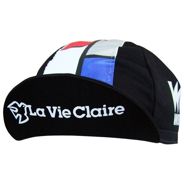 The La Vie Claire Retro Cycling Cap is black with La Vie Claire printed in white on the brim and features vintage geometric patterns in red, blue, and white on top.