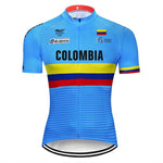 The image features the Colombia Team Cycling Jersey, crafted from lightweight polyester in blue. It prominently displays Colombia on the front with horizontal yellow, blue, and red stripes, plus official logos and the Colombian flag on the chest for authenticity.