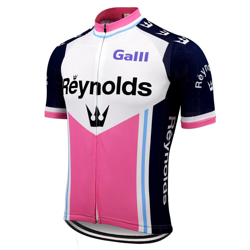 The Reynolds Galli 1981 Retro Cycling Jersey showcases a vibrant pink, white, and blue design with Reynolds on the front. Crafted from lightweight polyester, it features dark blue shoulders with white logos and includes a centered zipper and silicone waist strip for a snug fit.