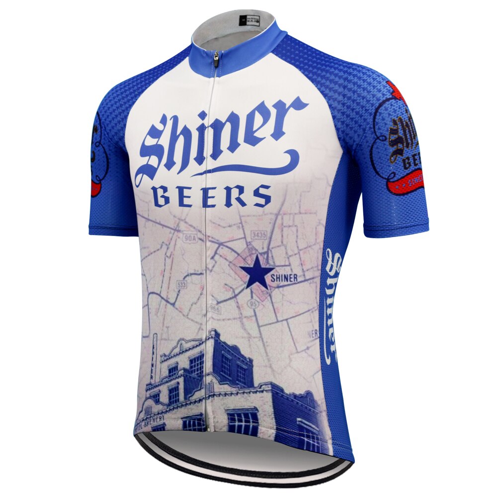 The Shiner Beers Retro Cycling Jersey features a blue and white retro beer-themed design with Shiner Beers text, map graphic with a star, building image at the bottom, and blue textured sleeves highlighted by red and blue logo accents.
